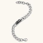 Silver 316L stainless steel Cuban chain bracelet with blackened skull and crown ID bar centerpiece, lobster clasp closure.