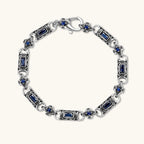 Oxidized silver stainless steel link bracelet with baguette blue CZ stones and intricate scroll engravings, lobster clasp.