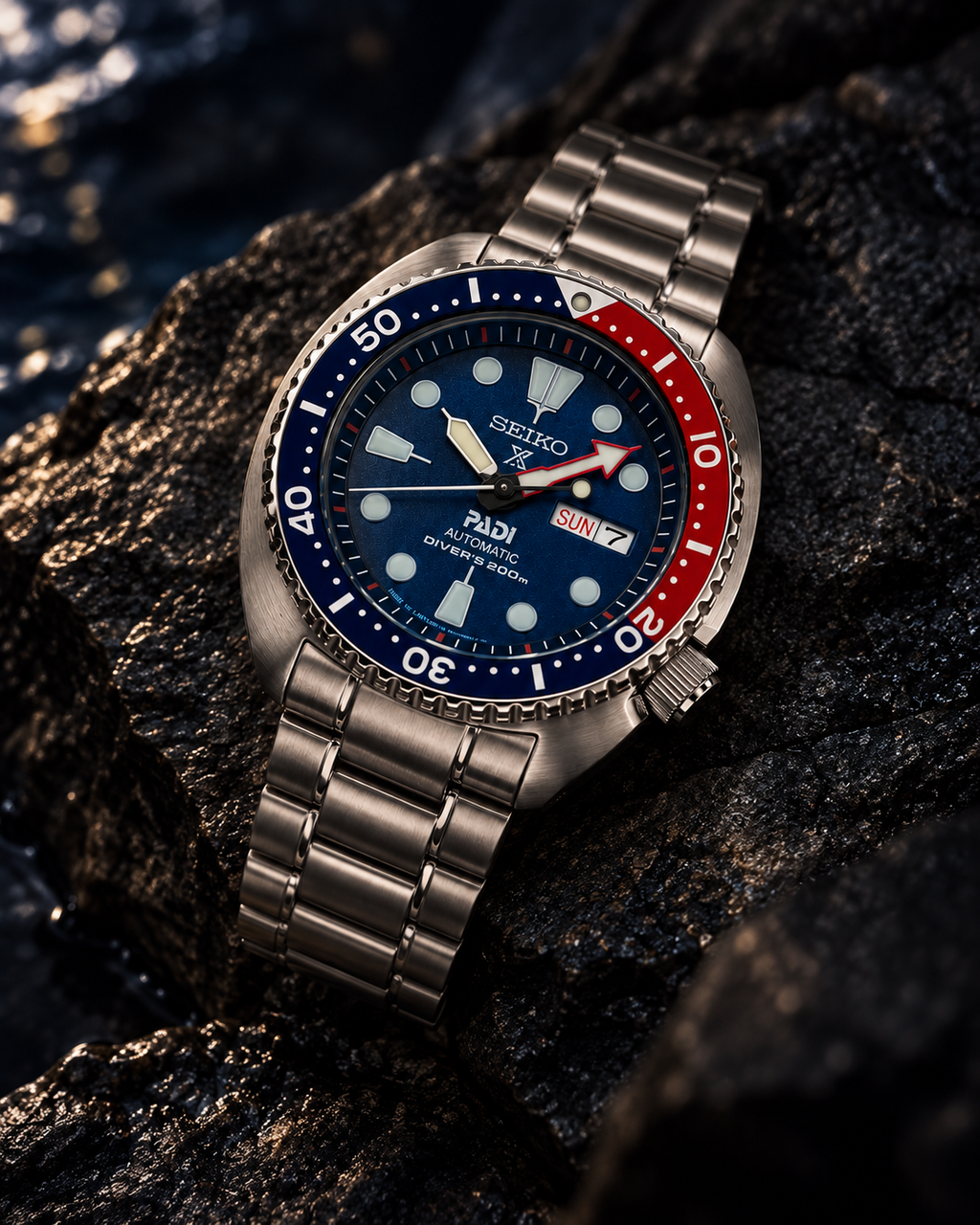 Seiko Prospex PADI Turtle SRPE99 automatic diver's watch on wet dark stone, blue dial and red-blue bezel