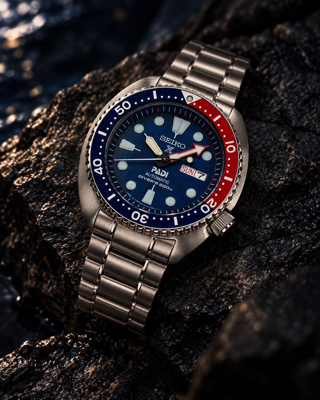Seiko Prospex PADI Turtle SRPE99 automatic diver's watch on wet dark stone, blue dial and red-blue bezel