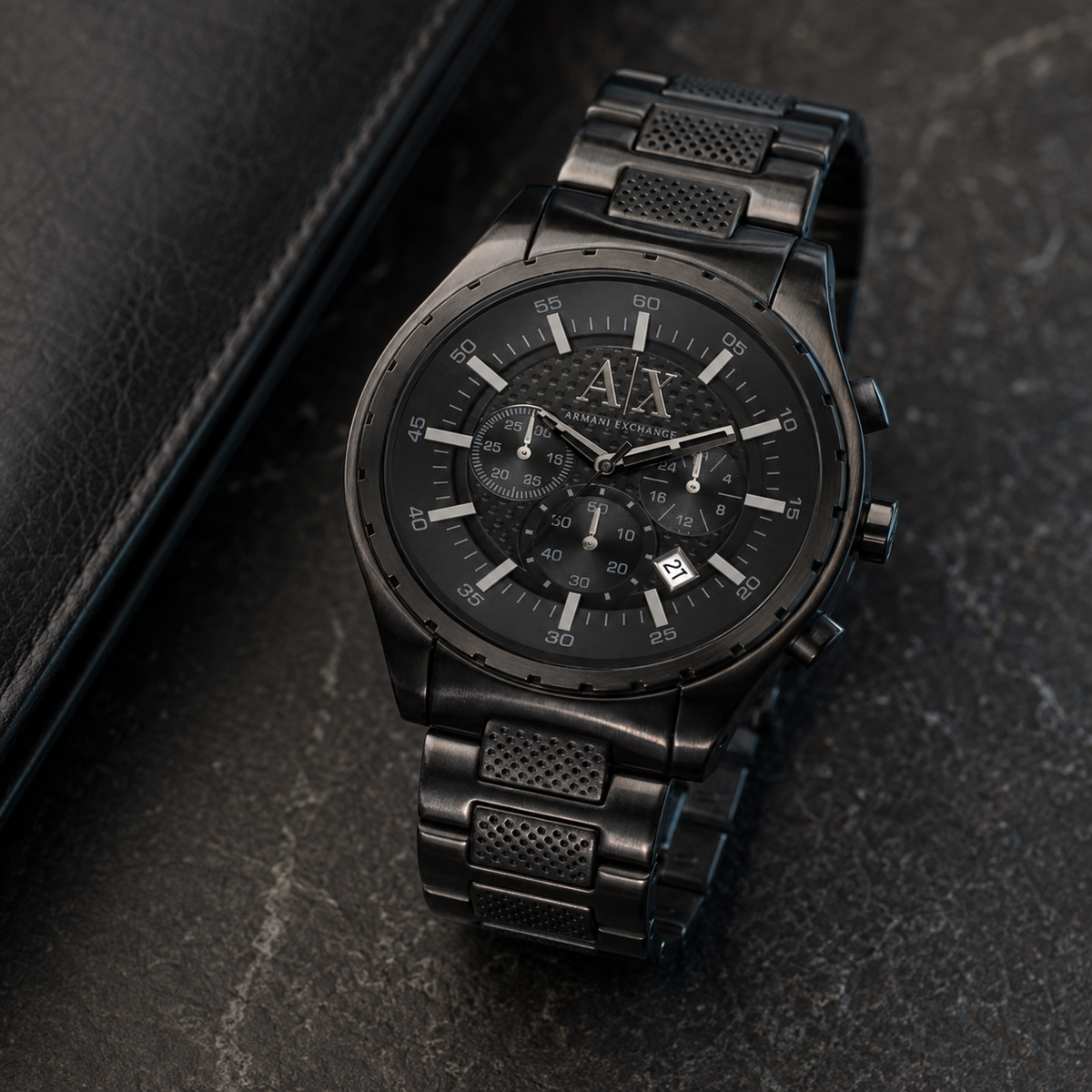 Armani Exchange AX1058 black chronograph watch on a dark desk
